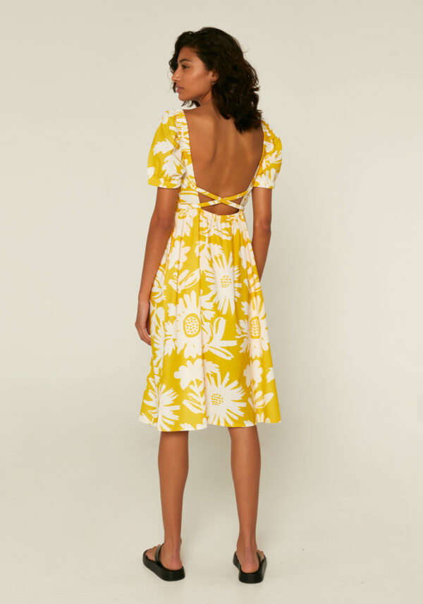 Back photo, model is wearing yellow print dress with cross back straps