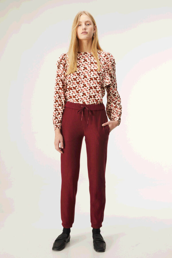 Model wears burgundy trousers